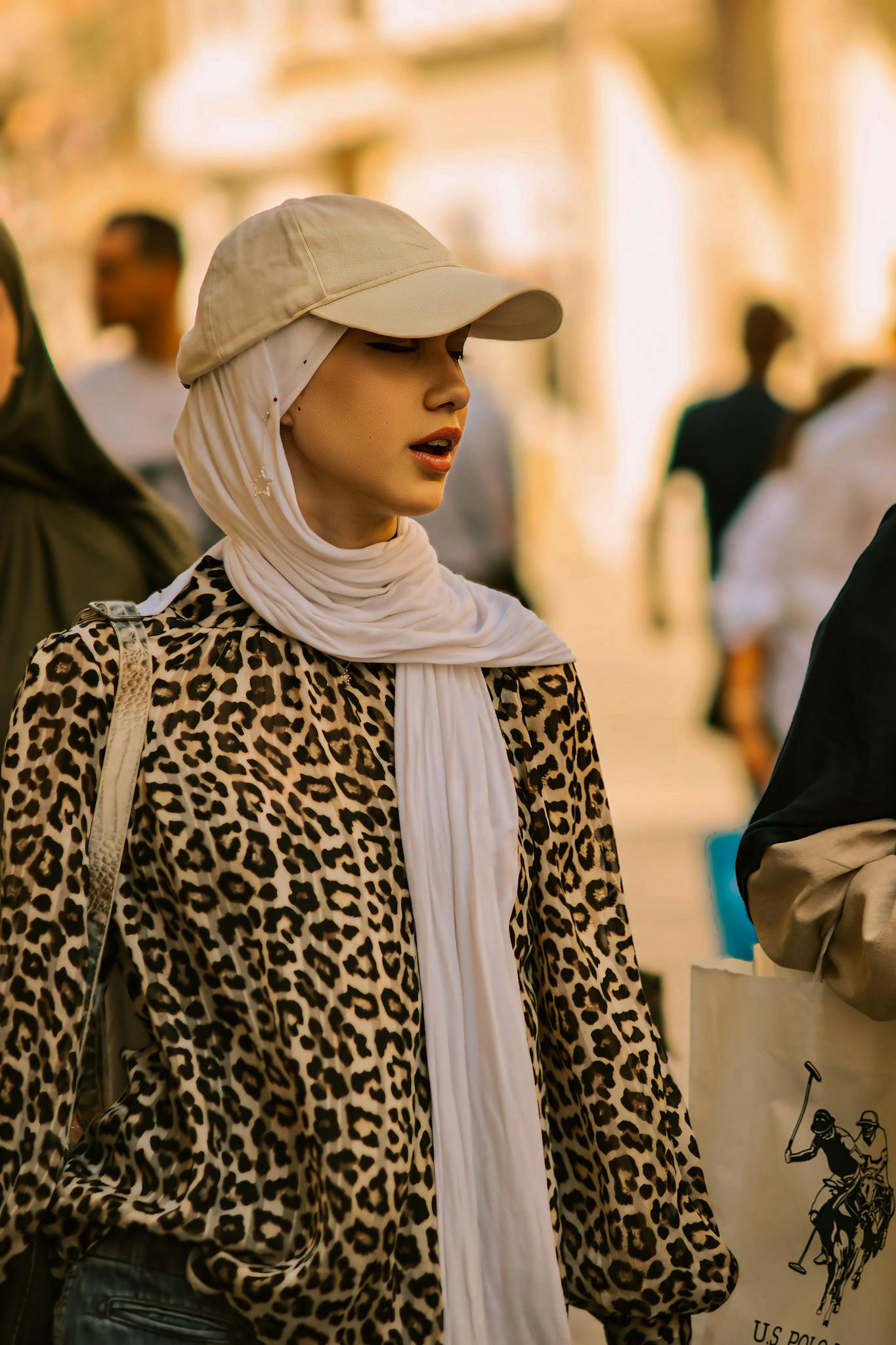 Fashion-forward woman in leopard print shirt and scarf walking on a busy outdoor street.