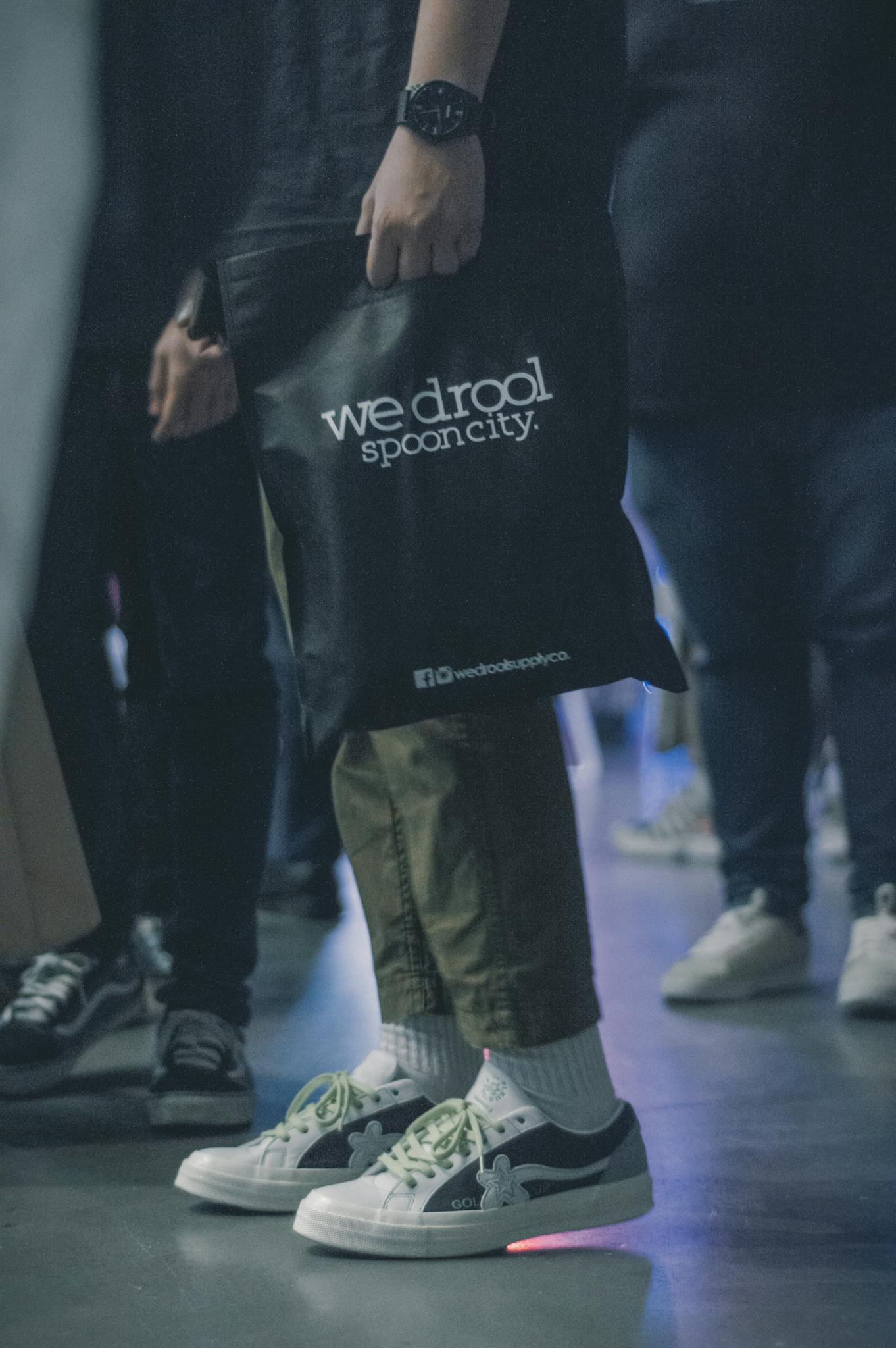 Stylish casual outfit with sneakers and tote bag at a fashion event, showcasing modern urban style.